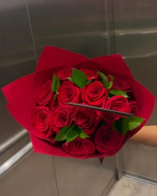 Ramo de rosas rojas en papel rojo, entregado en un ascensor