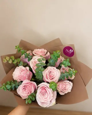 Ramo de rosas rosadas en papel kraft, sostenido en mano